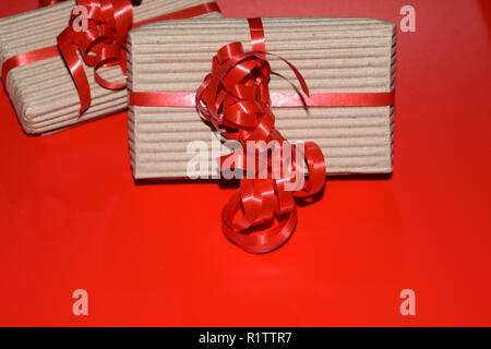 Geschenkboxen für Weihnachten mit Kopie Raum, Blick von oben auf die Schachtel aus Karton verpackung mit roter Schleife auf rote Oberfläche verpackt Stockfoto