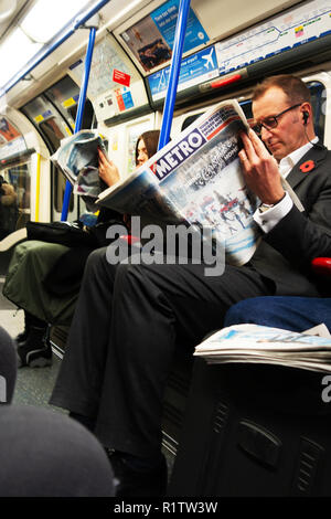 U-Bahn Pendler Zeit, Pendler, die Londoner Zeitung lesen in der Londoner U-Bahn U Stockfoto