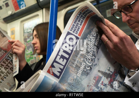 U-Bahn Pendler, Nahaufnahme der männlichen und weiblichen Pendler lesen Kostenlose London Zeitung auf dem Londoner U-Rohr in England Stockfoto