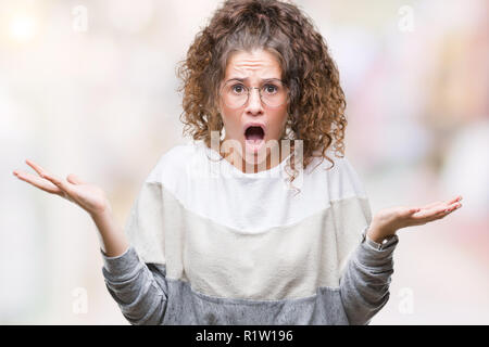 Schöne Brünette lockige Haare junge Mädchen Tragen einer Brille über isolierte Hintergrund feiern verrückt und crazy für den Erfolg mit erhobenen Armen und geschlossenen Ey Stockfoto