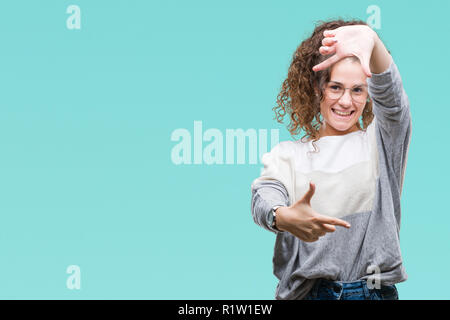 Schöne Brünette lockige Haare junge Mädchen Tragen einer Brille über isolierte Hintergrund lächelnd, Rahmen mit Händen und Fingern, glückliches Gesicht. Creativ Stockfoto