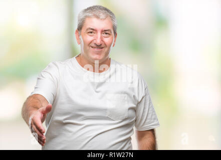 Gut aussehender älterer Mann über isolierte Hintergrund lächelt freundlich mit Handshake als Ansage und einladend. Erfolgreiches Business. Stockfoto