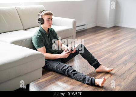 Ein junger attraktiver Mann spielen Videospiele in einem Sofa Stockfoto