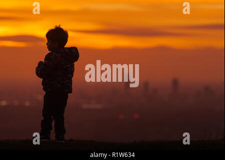 Ein vier Jahre alter Junge schaut über Manchester City Centre in der Ferne bei Sonnenuntergang von der Walliser Dorf Mossley am Mittwoch, 14. November 2. Stockfoto