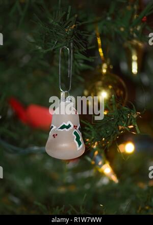 Urlaub Glocke hängen am Weihnachtsbaum mit gelben Baum Lichter im Hintergrund. Stockfoto