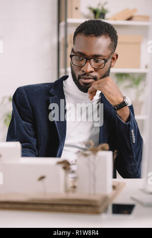 Nachdenklich afrikanischen amerikanischen Architekten arbeiten mit Business Gebäude Modell Stockfoto