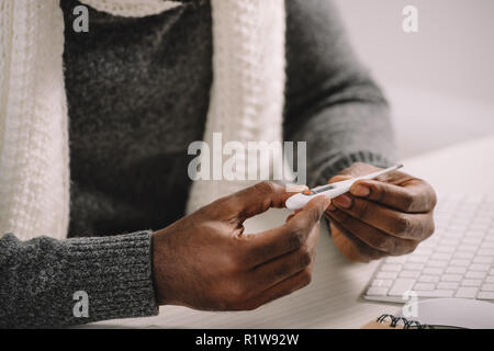 Teilweise mit Blick auf die kranken afrikanischen amerikanischen Mann, elektronische Thermometer Stockfoto