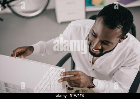 Hohe Betrachtungswinkel von lächelnden schönen afrikanischen amerikanischen Architekten Architektur Modell im Büro suchen Stockfoto