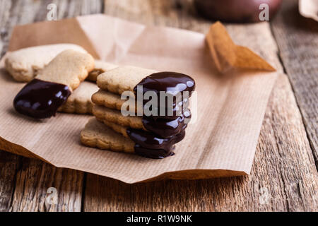 Handgemachte Schokolade getauchte Plätzchen und geschmolzene dunkle Schokolade auf rustikalen Holztisch Stockfoto