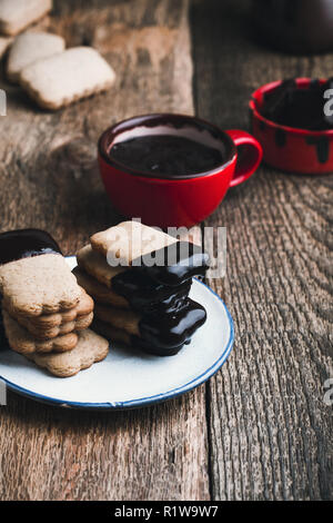 Handgemachte Schokolade getauchte Plätzchen und geschmolzene dunkle Schokolade auf rustikalen Holztisch Stockfoto