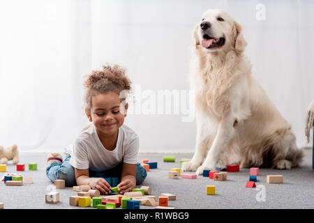 Adorable african american Kind spielen mit Spielzeug Würfel und Hund Stockfoto
