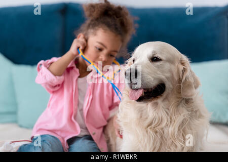 Adorable african american Kid spielen mit Stethoskop und ihr Retriever Stockfoto