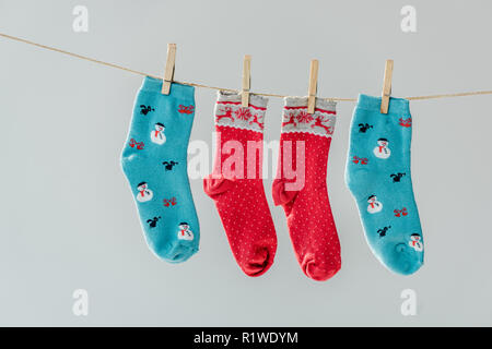 Nahaufnahme der bunten Festliche winter Socken hängen auf Wäscheleine mit Wäscheklammern isoliert auf Grau Stockfoto