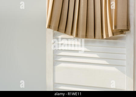 Nahaufnahme der beige Faltenrock an den weißen Raumteiler isoliert auf Grau Stockfoto