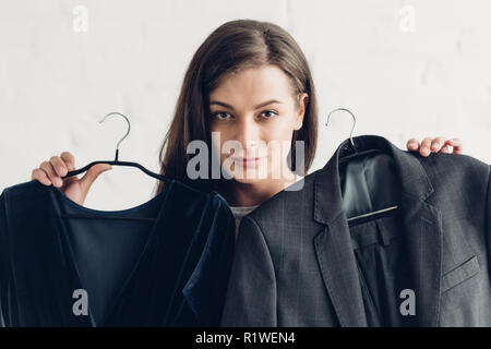 Nahaufnahme Porträt der jungen Transgender Mann Betrieb männliche Anzug und Kleid vor der weißen Wand Stockfoto