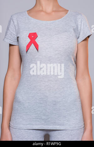 7/8 Schuß von Frau im grauen T-Shirt mit AIDS-Prävention red ribbon auf grauem Hintergrund Stockfoto