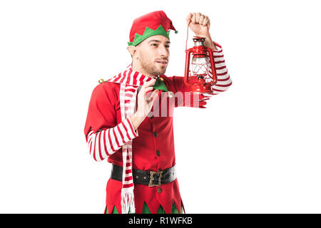 Mann in der Weihnachtself kostüm an der roten Laterne auf weißem Hintergrund suchen Stockfoto