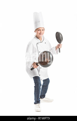 Junge in Weiß chef Uniform und Mütze holding Pfannen isoliert auf weißem Stockfoto