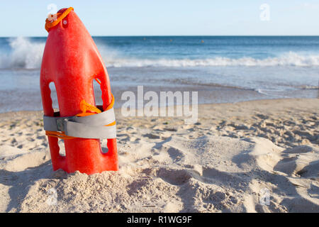 Orange Rescue Buoy auf Sand Strand gepflanzt. Meer Webt als Hintergrund Stockfoto
