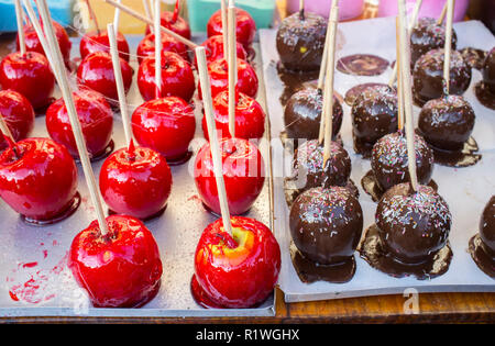 Äpfel in einem Karamell Weihnachtsmarkt abgewürgt. Zwei Sorten, Schokolade und Karamell, über Zinn Fach. Stockfoto