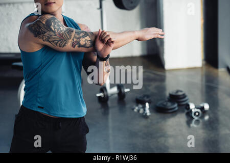 7/8-Ansicht der jungen Sportler zu tun stretching Training im Fitnessstudio Stockfoto