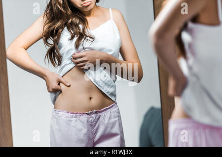 7/8-Ansicht der traurige Frau an ihrer Taille in Spiegel Stockfoto