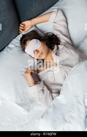 Attraktive junge Frau schlafen in Augenmaske im Bett Stockfoto