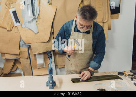 Männer mittleren Alters Handtasche Handwerker arbeiten mit Hammer im Studio konzentrierte Stockfoto