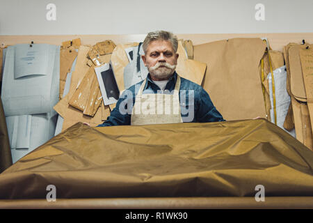 Zuversichtlich Männer mittleren Alters Handtasche Handwerker setzen Gewebe auf die Tabelle im Studio Stockfoto