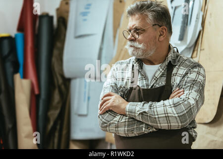 Reifen Handwerker in Schürze und Brillen Stehen mit verschränkten Armen im Studio Stockfoto