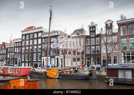 Bunte traditionelle Häuser und Boote auf dem Kanal in Amsterdam, Niederlande günstig Stockfoto