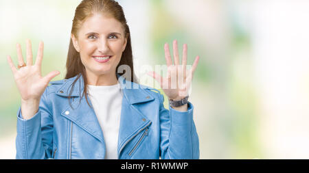 Schöne, reife Frau mittleren Alters tragen Mode Leder Jacke über isolierte Hintergrund angezeigt und zeigen mit den Fingern Nummer zehn, während Smilin Stockfoto