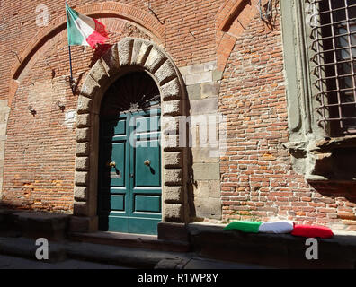 Drei Kissen in Grün, Weiß und Rot wie die italienische Flagge neben einem grünen Holztür Stockfoto