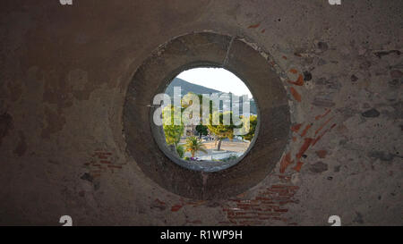 Blick durch ein rundes Fenster in einer Steinmauer zum Dorf Lipari in Italien Stockfoto