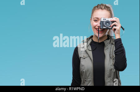 Junge blonde Frau, Aufnahme von Bildern mit Vintage Kamera über isolierte Hintergrund mit einem glücklichen Gesicht stehen und lächelnd mit einem selbstbewussten Lächeln angezeigt Stockfoto