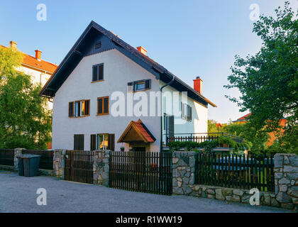 Wohnhäuser mit Zaun und Hof entlang der Straße in der Straße von Maribor in Slowenien. Stockfoto