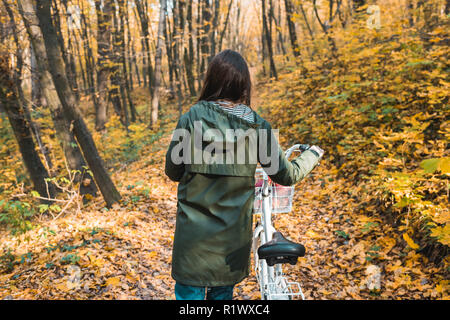 Rückansicht der Mädchen mit dem Fahrrad in Gelb herbstlichen Wald Stockfoto