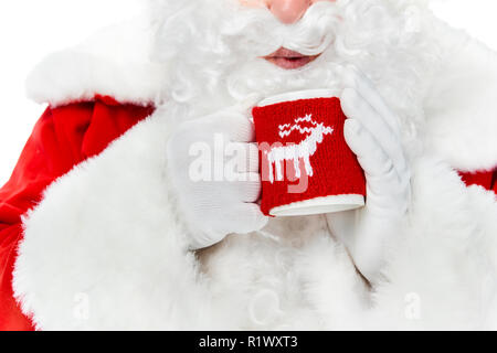 7/8-Ansicht von Santa Claus mit weißen Bart das Blasen auf heißen Getränk in Schale isoliert auf weißem Stockfoto