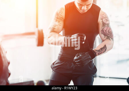 7/8-Ansicht der jungen Sportler Boxhandschuh im Fitnessstudio im Sonnenlicht Stockfoto