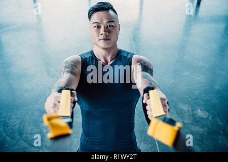 Junge muskulöse asain Sportler Training mit Widerstand Bänder in der Turnhalle konzentriert Stockfoto