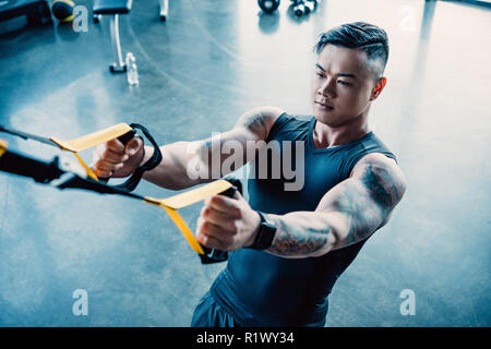 Junge muskulöse Sportler Training mit Widerstand Bänder in der Turnhalle konzentriert Stockfoto