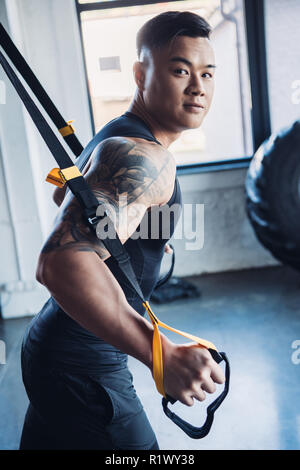 Jungen asiatischen muskulöse Sportler Training mit Widerstand Bänder in der Turnhalle konzentriert Stockfoto