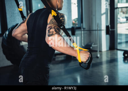 Blick auf junge muskulöse Sportler Training mit Widerstand Bänder in der Turnhalle 7/8 Stockfoto