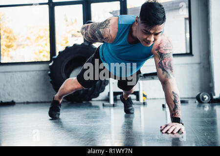 Die jungen Sportler einen Arm plank Übung im Fitnessstudio Stockfoto