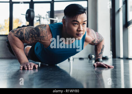 Jungen asiatischen Sportler tun plank Übung im Fitnessstudio konzentriert Stockfoto