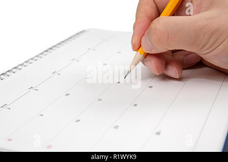 Eines Mannes Hand mit einem Bleistift in der Hand und Schreiben auf einen Kalender. Stockfoto