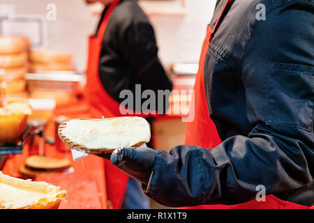 Person verkaufen Toastbrot mit Raclette Käse in der Nacht Weihnachtsmarkt am Gendarmenmarkt im Winter Berlin, Deutschland. Stockfoto