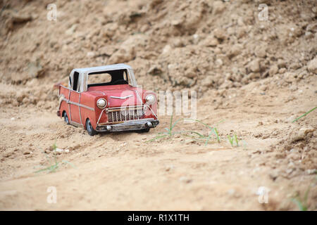 Ein Foto von einer auf alten metallischen Spielzeugauto auf sandigen Weg Stockfoto