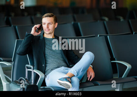 Städtischen Geschäftsmann auf Smartphone-Reisen im Inneren in Flughafen im Gespräch. Junger Mann mit Handy am Flughafen warten auf Boarding. Stockfoto