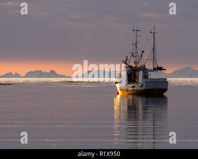 Angeln Boot schoß bei Sonnenuntergang mit den Bergen der Lofoten im Hintergrund, geschossen von Mjelle außerhalb von Bodø. Stockfoto